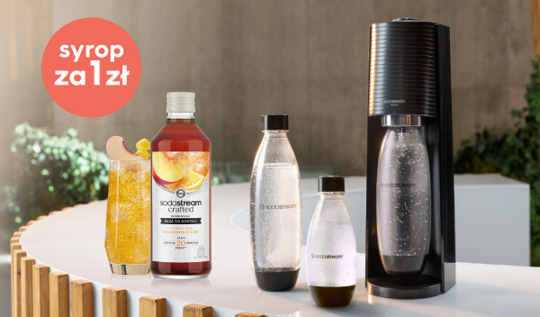 Zestaw produktów do przygotowywania napojów gazowanych, w tym syrop o smaku brzoskwiniowo-imbirowym z napisem Sodastream crafted oraz dwie butelki z wodą gazowaną. W lewym górnym rogu widnieje czerwone kółko z białym napisem Syrop za 1 zł, a po prawej stronie znajduje się urządzenie do gazowania wody.